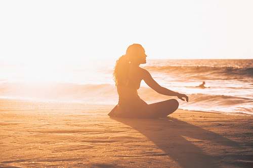 yoga silhouette of woman sitting by the seashore during sunset exercise